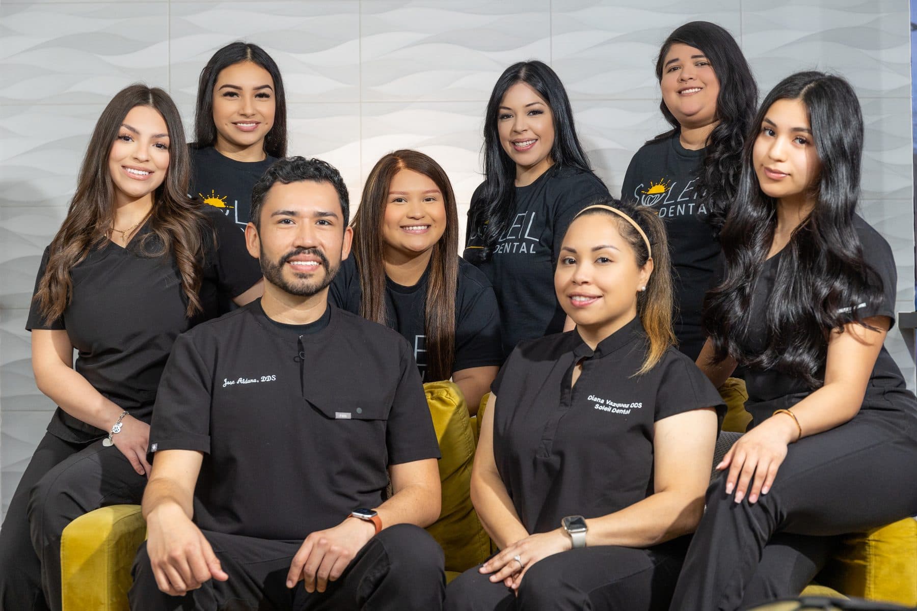 The Soleil Dental team together on the yellow sofa in the Oak Lawn office