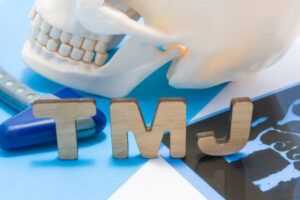 TMJ letters, human skill, and X-ray on blue table