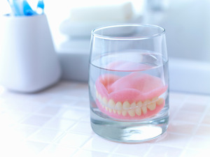 Dentures soaking in glass on bathroom counter